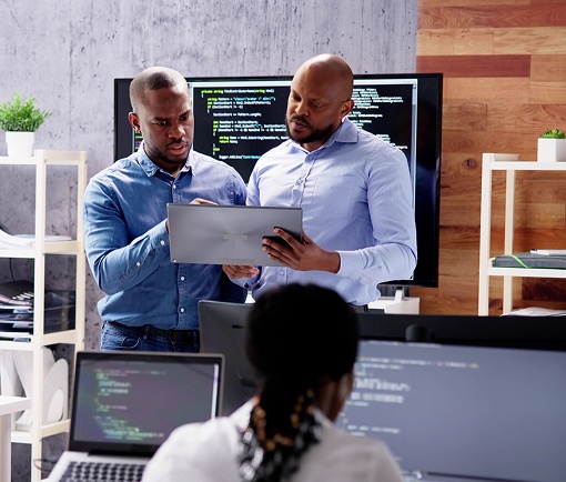 Two men collaborating in front of a computer screen, discussing information displayed on the monitor.