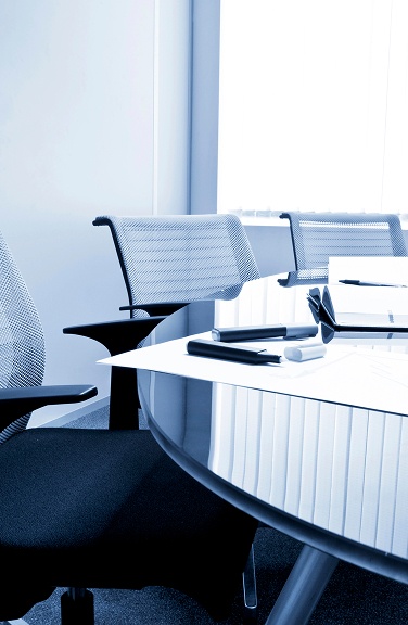 A conference room featuring a large table surrounded by several chairs.