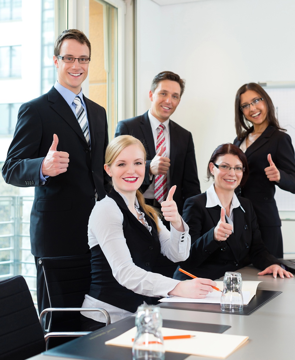 A diverse group of five people smiling and posing together for a photo outdoors.