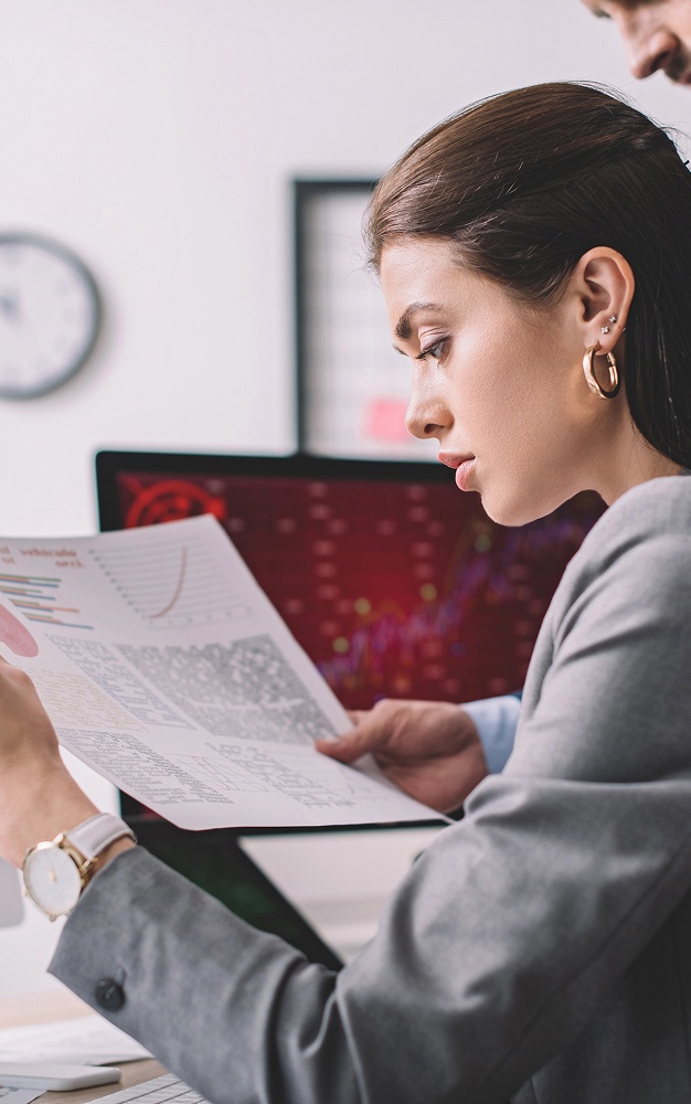 A man and woman examine a paper displaying a chart, discussing its details and implications.