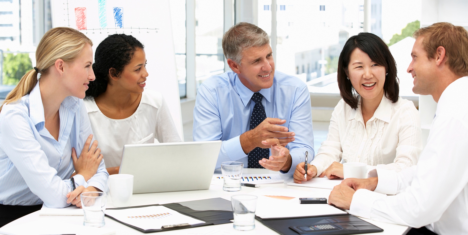 A diverse group of business people engaged in discussion around a conference table.