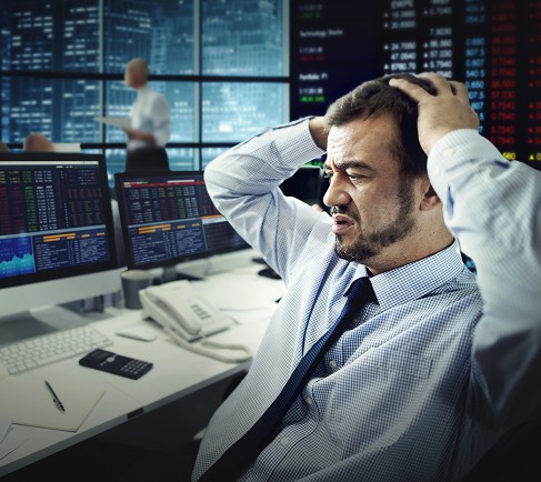 A man sitting at a desk, visibly distressed, with his head in his hands, suggesting feelings of overwhelm or frustration.